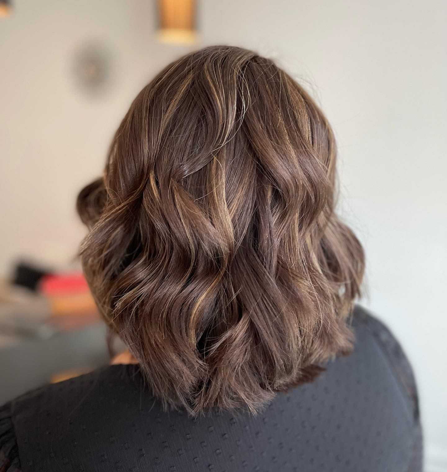 Wavy brown hair with subtle highlights, styled in a shoulder-length bob.