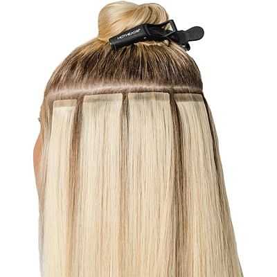 Hair extensions being applied to blonde hair using a clip-in method.